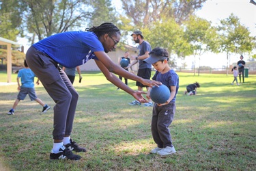 Instructor teaching child how to play with a blue ball